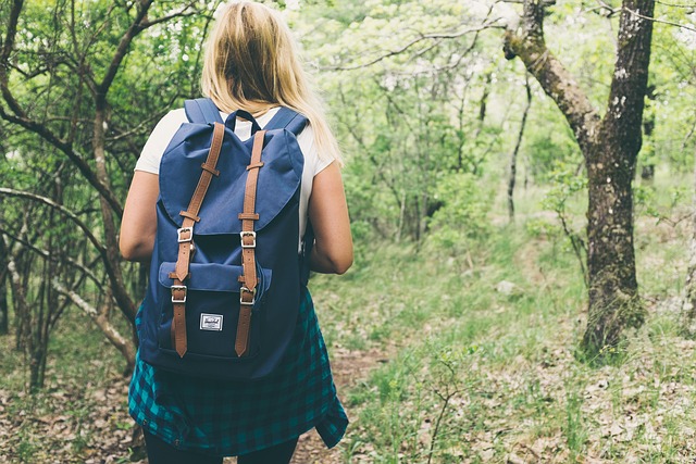 Woman walking through the woods with a backpack on.